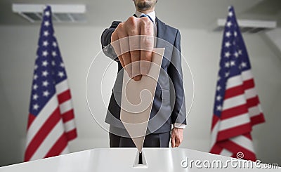 Election or referendum in United States. Voter holds envelope in hand above ballot. USA flags in background Stock Photo