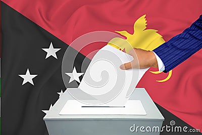 Elections in the country - voting at the ballot box. A man`s hand puts his vote into the ballot box. Flag Papua New Guinea on Stock Photo