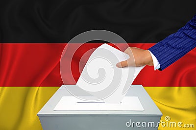 Elections in the country - voting at the ballot box. A man`s hand puts his vote into the ballot box. Flag germany on background Stock Photo