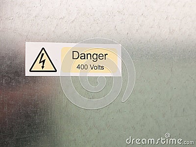 an electric bolt in triangle white yellow and black safety caution sign warning saying danger 400 volts attached to a metal wall Stock Photo