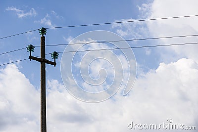 Electric cables sustained by a concrete pole, against the blue sky with white clouds Stock Photo