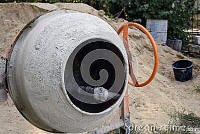 Electric concrete mixer on the background of a heap of sand. Construction machinery at the production site Stock Photo