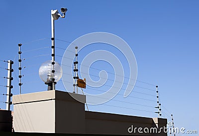 Electric Fence and Security Camera Atop Boundary Wall Stock Photo