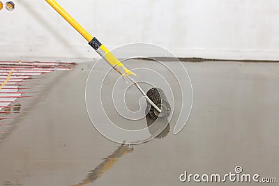 Electric floor heating system installation in new house. Roller for pouring concrete floor. Stock Photo