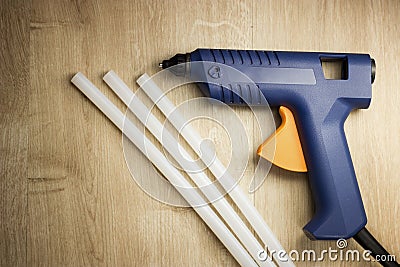 Electric glue gun with silicone sticks on a wooden surface Stock Photo