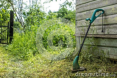 Electric grass trimmer stands in the garden near the house Stock Photo