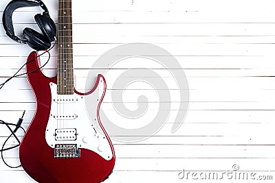 Electric guitar with headphones on white wooden table. Copy space. Stock Photo