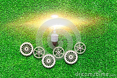 Electric light bulb, gears on the background of artificial green grass. Stock Photo