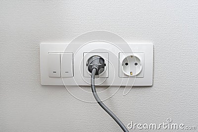 Electric light switch and socket on the empty wall, electrical power socket and plug switched. The concept of energy savings Stock Photo