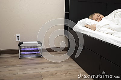 Electric Mosquito or Insect Zapper With Blue Purple Lights Turned on near Sleeping Person Stock Photo