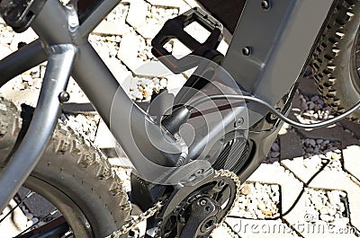 Electric mountain bike is charging, with the plug inserted to recharge the battery. Detail. Stock Photo