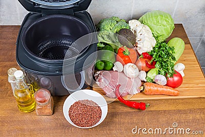 Electric multi-cooker with empty pot among of raw foods Stock Photo