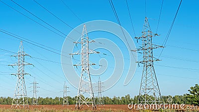 Electric power transmission on the background of blue sky. Technogenic landscape. Transmission tower or an electricity pylon Stock Photo