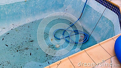 Electric pump in bottom of dirty leaking swimming pool removing water so the pool can be repaired Stock Photo