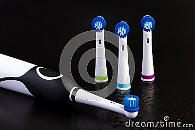 Electric rechargeable toothbrush with three toothbrush heads on black Stock Photo