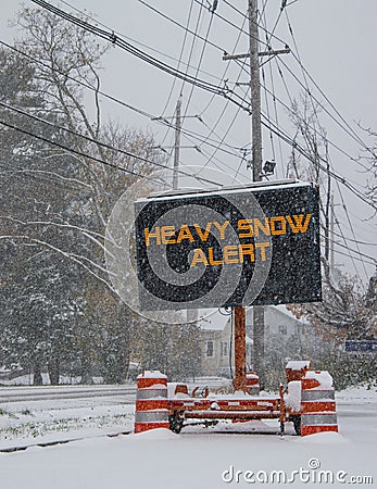 Electric road traffic mobile sign by the side of a snow covered road with snow falling warning of heavy snow alert Stock Photo