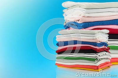 Electric steam iron and Pile of colorful clothes isolated on blu Stock Photo