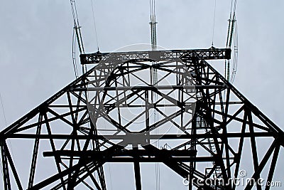 The electric transmission line pole is metallic with of connecting parts and wires on the sky background. Stock Photo