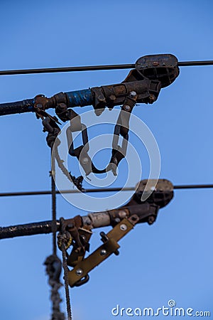 Electric trolleybus collectors close-up against the April blue spring sky. Power line wires network. Public transport. Stock Photo