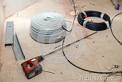 Electrical cable, wire, insulation, professional puncher with long drill, aluminum profile, construction debris on dirty tiled Stock Photo