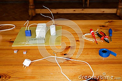 Electrical circuit with wires and spare parts, installation equipment, pliers, blue electrical tape, screwdrivers on the table Stock Photo