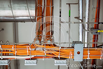 Electrical conduits system and metal pipeline installed on building ceiling, orange wires Stock Photo