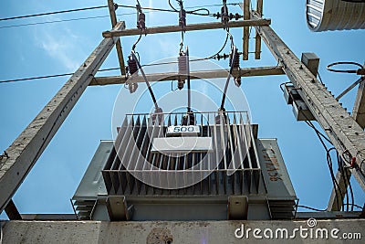 Electrical distribution transformer with high voltage cables and protection equipment install on concrete pole with blue sky Stock Photo