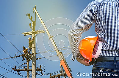 Electrical engineer holding safety helmet with electricians working on electric power pole with crane Stock Photo