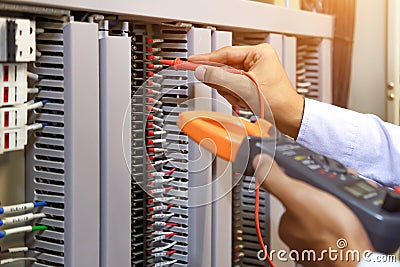 Electrical engineer using digital multi-meter to check current voltage at circuit breaker Stock Photo
