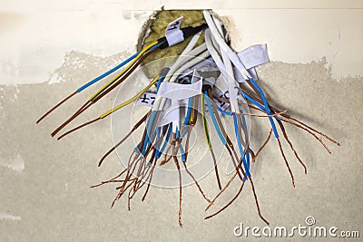 Electrical exposed connected wires protruding from socket on white wall. Electrical wiring installation. Finishing works in Stock Photo