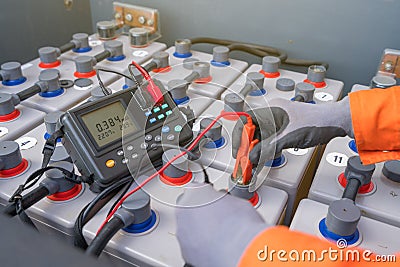 Electrical and instrument technician measuring voltage and internal resistance of battery. Stock Photo