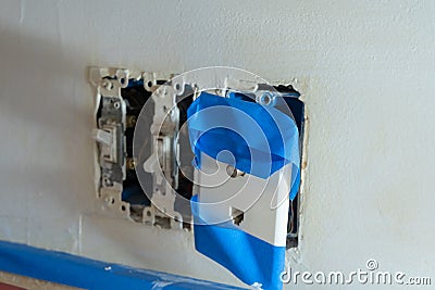 Electrical outlets light switch, phone jack and cable covered in painters tape with covers removed, due to home renovations and Stock Photo