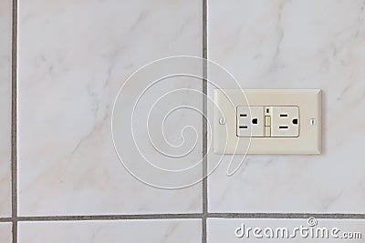 Electrical plug type B on the tiled wall in a bathroom. Stock Photo