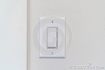 Electrical rocker light switch with flat broad lever on white interior wall Stock Photo