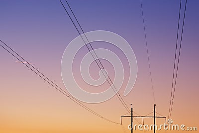 Electrical wires against the dawn sky, in the background two pillars, focusing on the wires, concept Stock Photo