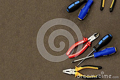Electrical wiring repair set desired tool design art industrial blue screwdriver red nippers on a dark brown border right Stock Photo