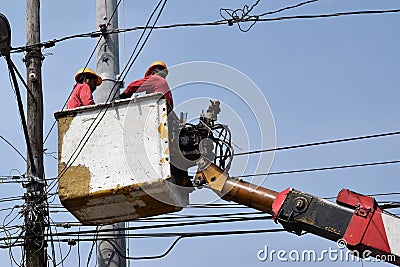 Electrical Workers On Telehandler With Bucket installing High tension wires on tall concrete post. Underside view low angle Editorial Stock Photo