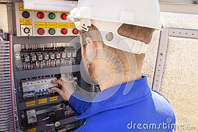 The electrician adjusts the electrical cabinet. engineer in helmet is testing electrical equipment Stock Photo