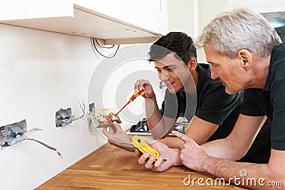 Electrician With Apprentice Working In New Home Stock Photo