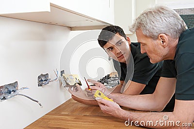 Electrician With Apprentice Working In New Home Stock Photo