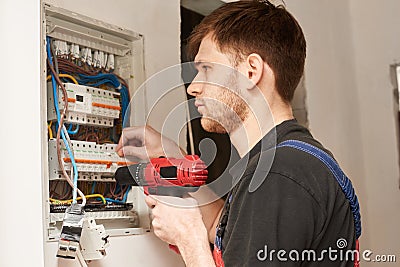 Electrician builder engineer screwing equipment in fuse box Stock Photo