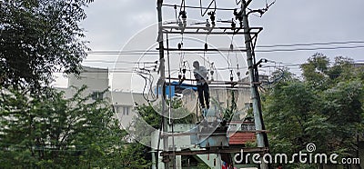 Electrician climbed up and fixing the problem in high voltage transformer without proper safety gears Editorial Stock Photo