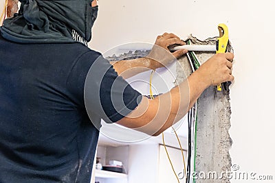 Electrician concealing electicity power wire lines within plastic tube embeded into wall Stock Photo