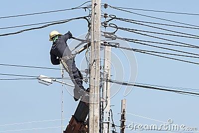 Electrician connects wires on a pole against blue sky Editorial Stock Photo