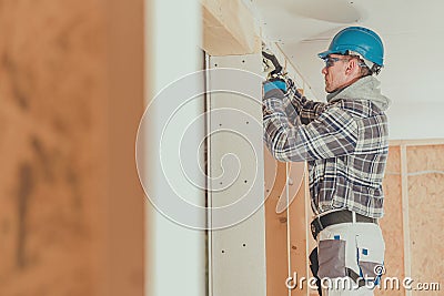 Electrician Contractor Feeding Electric Wire Through Wooden Framing Stock Photo