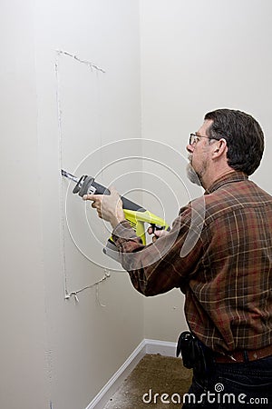 Electrician cutting access hole Stock Photo