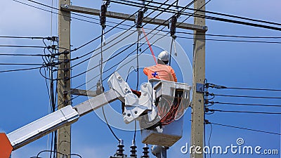 Electrician with disconnect stick tool on crane truck working to install electrical transmission on power pole Stock Photo