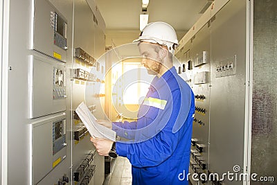 Electrician Engineer on control panel with electric scheme. Maintenance of electrical equipments Stock Photo