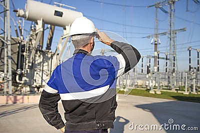 Electrician engineer on power electric station look at industrial equipment. Technician in helmet on electro substation Stock Photo