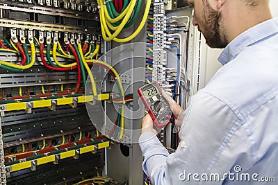 Electrician engineer testing cabling connection of high voltage power electric line in industrial distribution fuse board Stock Photo